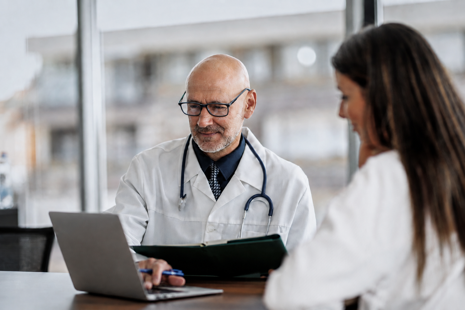 Medico in camice bianco allo studio con laptop in ambiente clinico